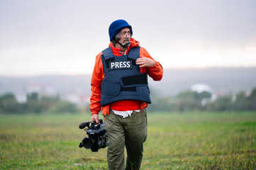 Reporter in bulletproof vest holding a video camera