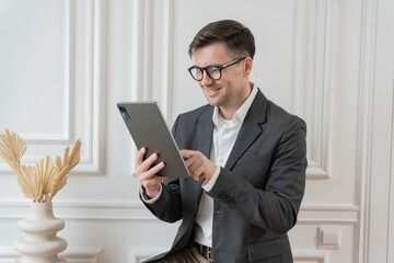 A professional attentively examines a tablet, his smart attire complementing the refined elegance...