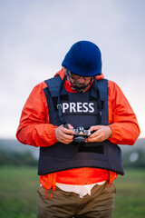 Reporter in bulletproof vest holding a camera.