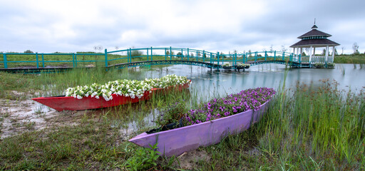 Riverside Beauty: Boat, Bridge, Gazebo, and Flowers - 773934744