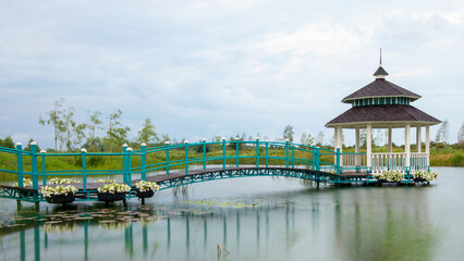Flowered Wharf: Boat, Bridge, and Gazebo on Riverbank - 773934755