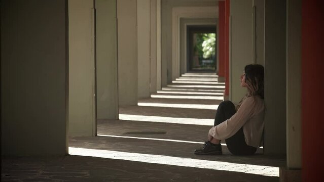 sad depressed young woman sitting at the entrance of a palace: fear, sadness