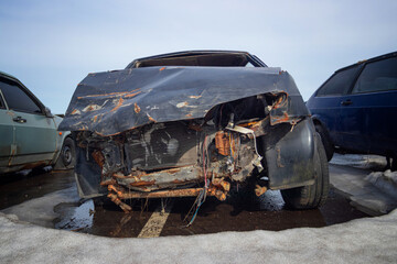 Broken and burnt cars after road accidents stand in a special parking lot