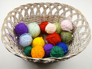 Colorful balls of wool for knitting  lie in a white wicker basket
