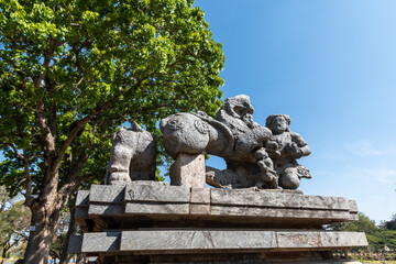 A ruined stone sculpture of a figure fighting a lion at the entrance to the ancient Hoysaleshwara temple complex in Halebidu in Karnataka.