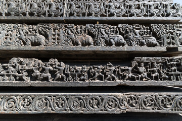 Ornate carvings of a war scene on a panel on the stone wall of the ancient Hoysaleshwara temple in Halebeedu.