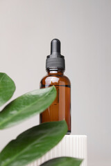 Glass dropper bottle with cosmetic oil, essential or serum on green background with leaf. Cosmetics with natural ingredients. Herbal homeopathic products