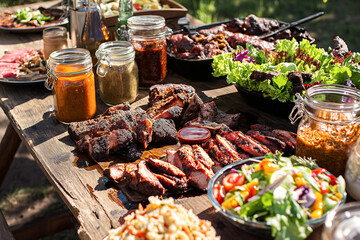 A table full of food including a salad, meat, and condiments