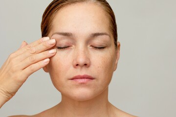 Middle aged caucasian woman of 40s with closed eyes holding finger on eyelid