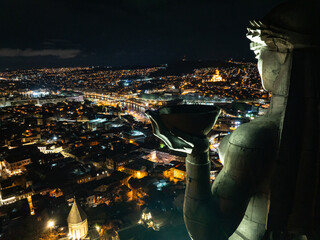 View across the city of Tbilisi, Georgia at night.. Aerial drone night photo of Tbilisi. Mother of...