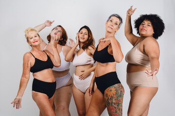 group of multiethnic women posing in underwear laughing having fun together, studio shot.