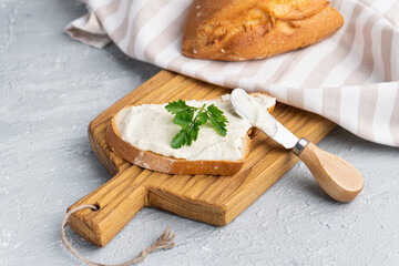 Fototapeta na wymiar Cream cheese with herbs and seasoning on slice of fresh crunchy rye bread with cheese knife nearby