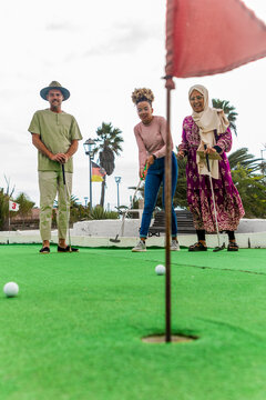 Diverse Group of Friends Enjoying Mini Golf Outdoors
