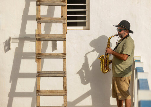 Street musician playing saxophone by a ladder