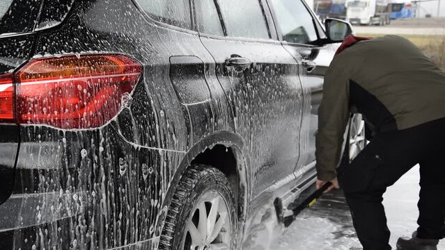 A man washes his car at a self-service car wash in spring