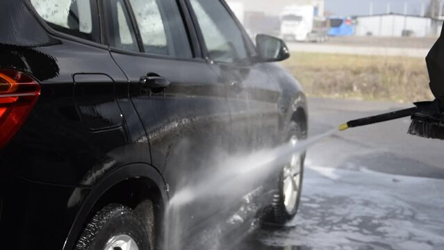 A man washes his car at a self-service car wash in spring