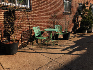 Green Patio Set Against Brick Wall on a Sunny Evening