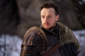 Prtrait medieval knight with sword in armor as style Game of Thrones in winter forest - 773975312