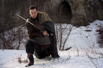 Medieval knight with sword in armor as style Game of Thrones in winter forest