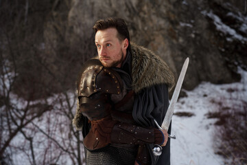 Medieval knight with sword in armor as style Game of Thrones in winter forest - 773975523