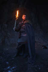 Medieval knight in armor with burning torch in cave - 773976984