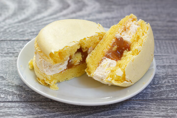 The sweet banana or lemon cake on saucer. Sliced pastry with white cream and yummy filling inside.