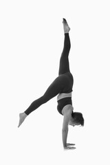 Parivrttasana variation, Ashtanga yoga  Side view of woman wearing sportswear doing Yoga exercise against white background. Black and white image.