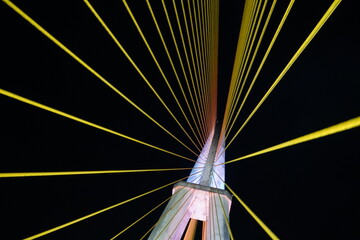 Background image of steel concrete pylon with illuminated yellow suspension cables of the Amazonas...