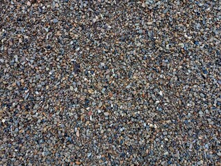The texture of small variegated river stones. The background is made of small stones of different colors sifted from fine sand.