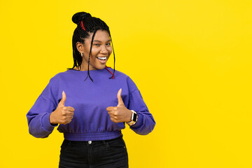 Afro woman giving a thumbs up gesture, dressed in casual purple attire against a vibrant yellow...