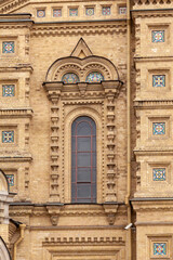 Fragment of the wall of an ancient Orthodox church with a picturesque window and decorative elements made of ceramics