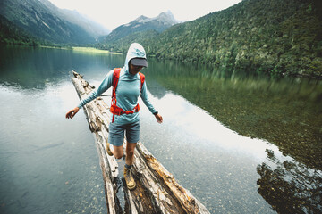 Hiking woman on a one plank bridge in high altitude mountains