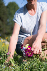 Junge Frau pfl&uuml;ckt Wiesenblumen Primeln und Wiesenschaumkraut im eigenen Garten im Fr&uuml;hling