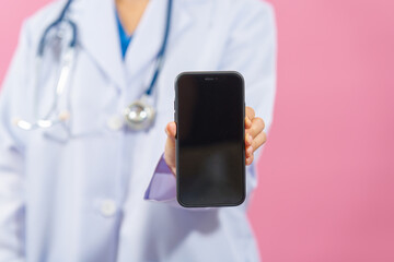 Holding mobile phone, Close up female medical doctor isolated on pink background.