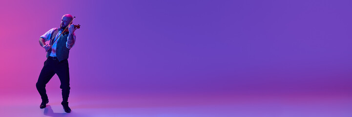 Full-length image of man, musician playing violin against gradient purple background in neon light. Concept of music, talent show, performance, concert, festival, instruments. Banner, ad © master1305