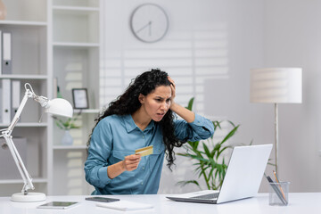 Worried Hispanic businesswoman working from home office reacts to a fraud or error on her credit...
