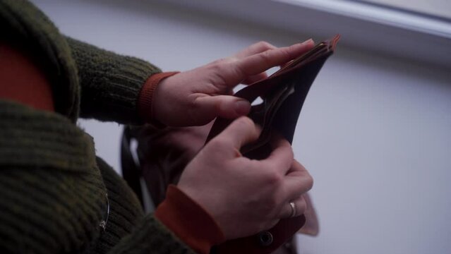 Distressed woman finds her wallet empty, no cash left. Financial crisis hits, job search urgent. Desperation, austerity visible in her empty purse, joblessness narrative relevant.