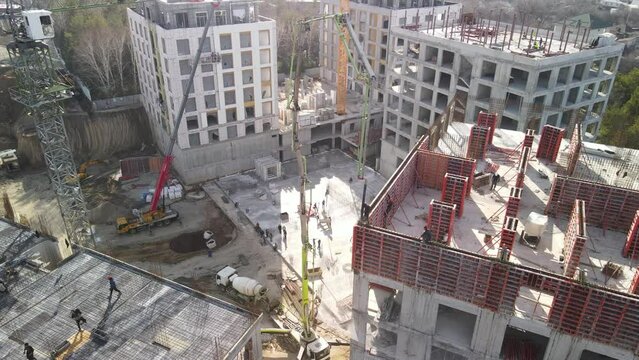 Aerial photography from a drone of a construction site for the construction of a multi-storey building, the process of pouring concrete. Construction of load-bearing walls.