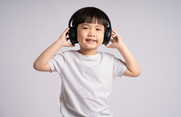 Portrait of an Asian boy listening music , posing  on a white background
