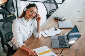 Technical support. In headphones. Businesswoman is indoors in the office