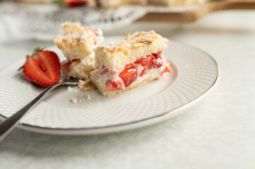 Piece of strawberry cake with chopped strawberries and whipped cream filling on a plate