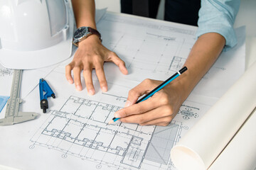 Architect at work on drafting blueprints for the interior design of a building in the office, focusing on structure and engineering