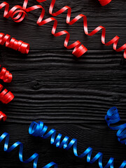 red and blue ribbon for celebration on a black wooden background - 774039712