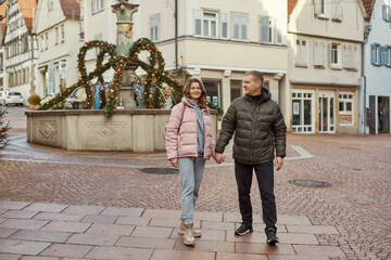 Obraz premium Loving couple of tourists walking around old town. Couple of lovers leisurely stroll in the cool autumn morning on the streets of a BIETIGHEIM-BISSINGEN (Germany). The guy holds his wife. Vacation