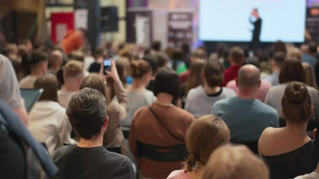 Crowd gathers at city event in conference room, sharing entertainment on stage
