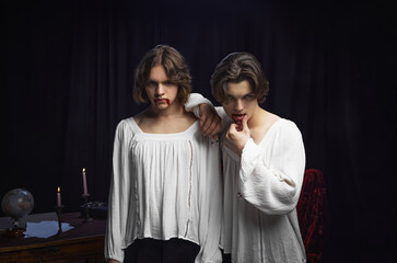 Fototapeta premium Two people with smudged lipstick resembling blood posing in white old-fashioned blouses against vintage background. Concept of comparisons of eras, renaissance, friendship, inspiration, afflatus.