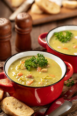 Bowls of split pea soup with ham and carrots garnished with parsley - 774046363