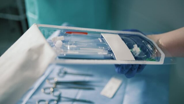 Person in blue gloves unpacking a tool for vein surgery