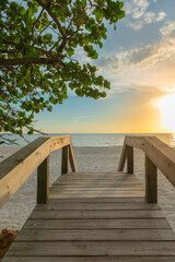 Fototapeta na wymiar Wooden bridge on the sandy beach at sunset. Naples Beach, Florida