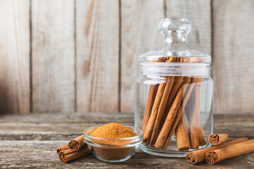 Ceylon cinnamon.Cinnamon sticks on a textured wooden background. Cinnamon roll and powder. Spicy spice for baking, desserts and drinks. Fragrant ground cinnamon. Close-up. Place for text. copy space - obrazy, fototapety, plakaty